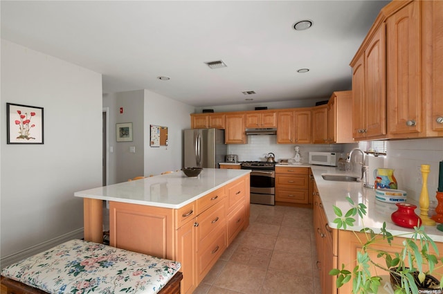 kitchen with a center island, sink, decorative backsplash, light tile patterned floors, and stainless steel appliances