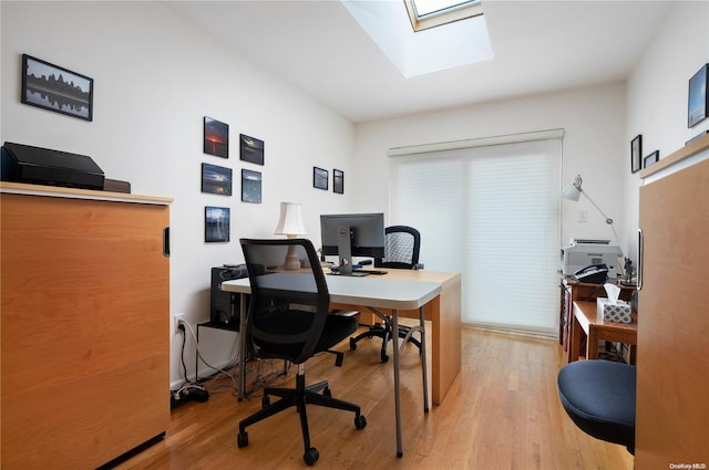 office area with light hardwood / wood-style floors and a skylight