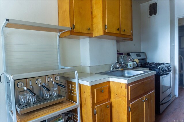 kitchen featuring gas stove, dark hardwood / wood-style flooring, and sink