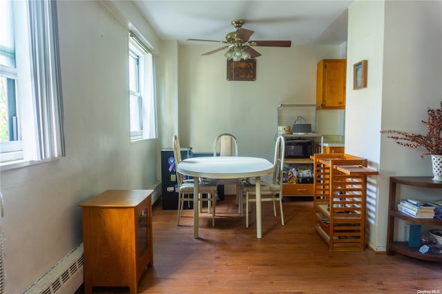 dining space featuring a baseboard radiator, a wealth of natural light, dark wood-type flooring, and ceiling fan