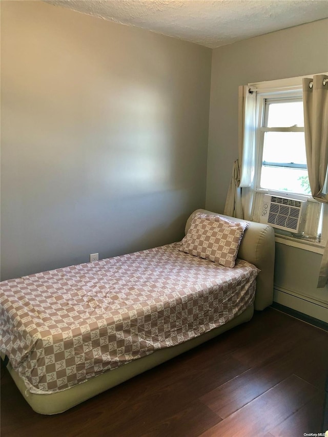 bedroom featuring a textured ceiling, dark hardwood / wood-style floors, cooling unit, and a baseboard heating unit