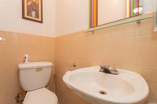 bathroom featuring toilet, tile walls, and sink