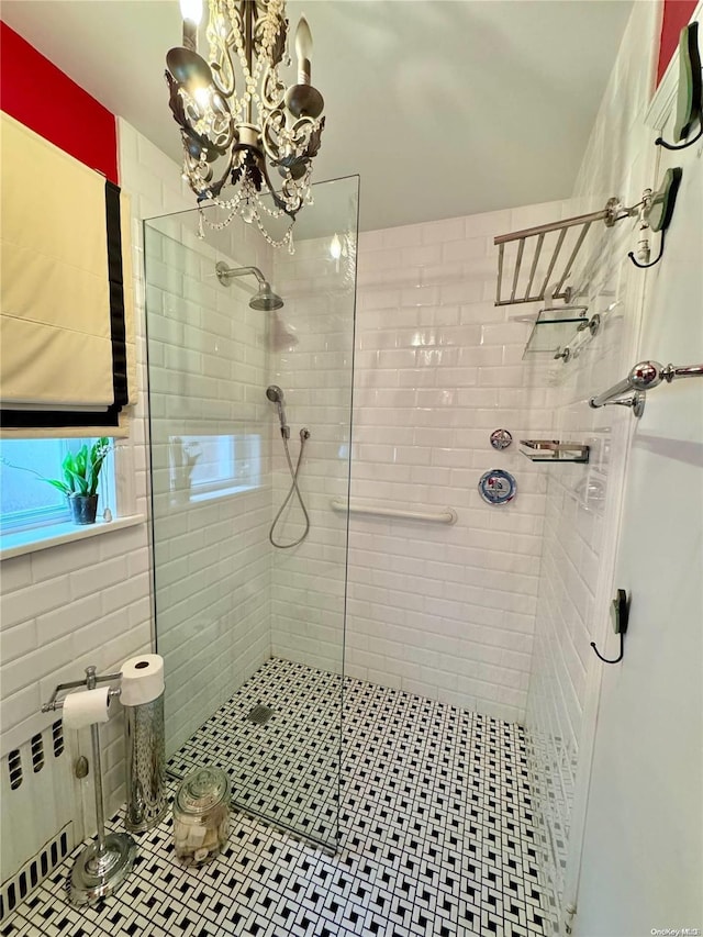 bathroom featuring tiled shower and an inviting chandelier