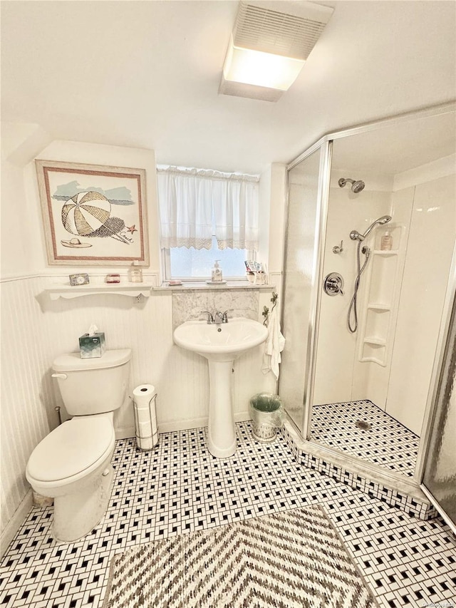 bathroom featuring a shower with door, tile patterned flooring, and toilet