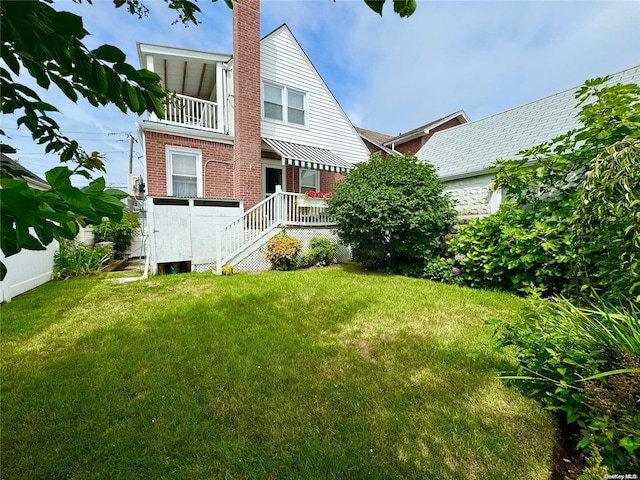 back of house with a yard and a balcony