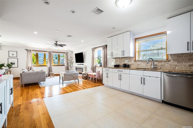 kitchen featuring white cabinetry, stainless steel dishwasher, a healthy amount of sunlight, and sink