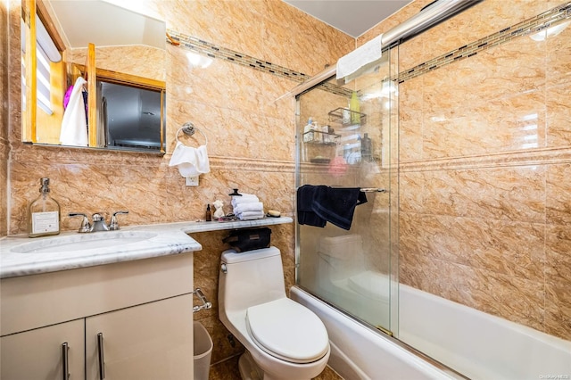 full bathroom with backsplash, toilet, shower / bath combination with glass door, vanity, and tile walls