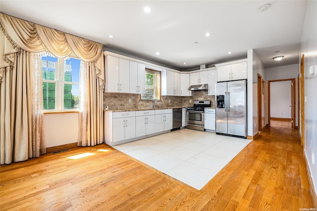 kitchen featuring light wood-type flooring, tasteful backsplash, stainless steel appliances, sink, and white cabinets