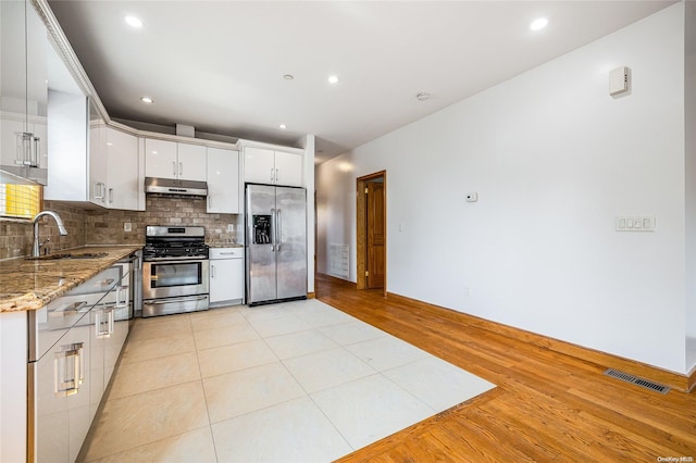 kitchen with stone counters, sink, light hardwood / wood-style flooring, white cabinetry, and stainless steel appliances