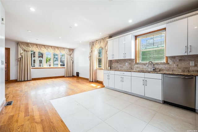 kitchen featuring decorative backsplash, stainless steel dishwasher, sink, light hardwood / wood-style floors, and white cabinetry