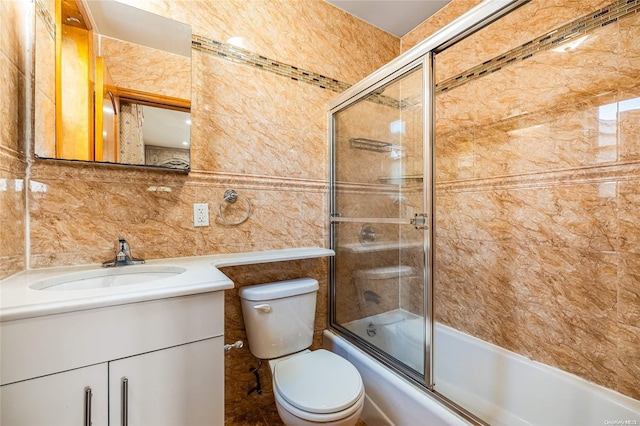 full bathroom featuring toilet, vanity, tile walls, and combined bath / shower with glass door