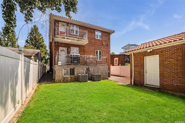 rear view of property with a lawn, a balcony, and cooling unit