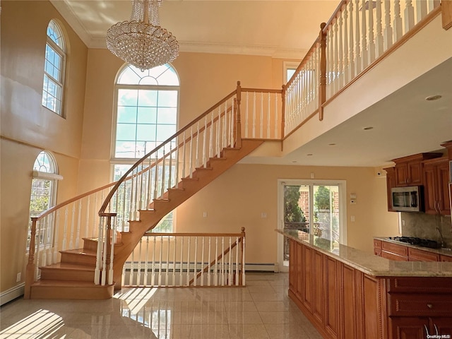 staircase featuring crown molding, a high ceiling, and an inviting chandelier