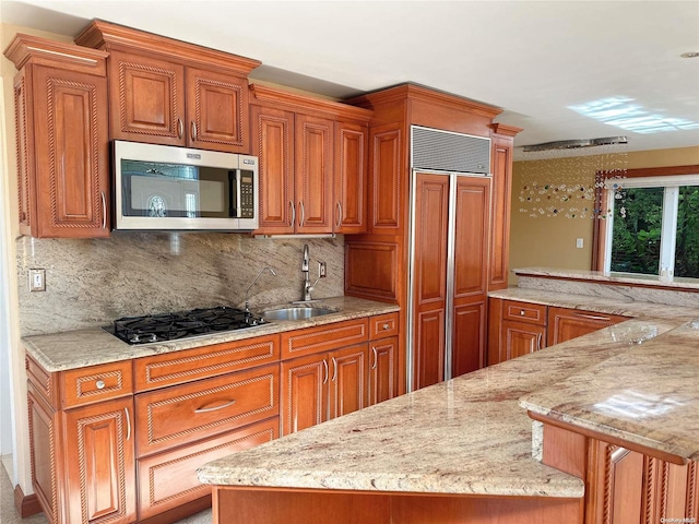 kitchen featuring decorative backsplash, black gas stovetop, light stone countertops, and sink