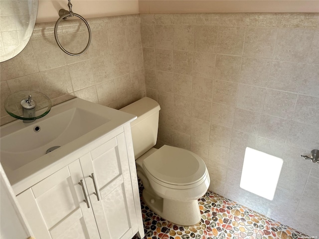 bathroom featuring tile patterned flooring, vanity, tile walls, and toilet