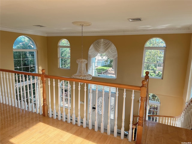 stairs with a chandelier, hardwood / wood-style floors, and crown molding