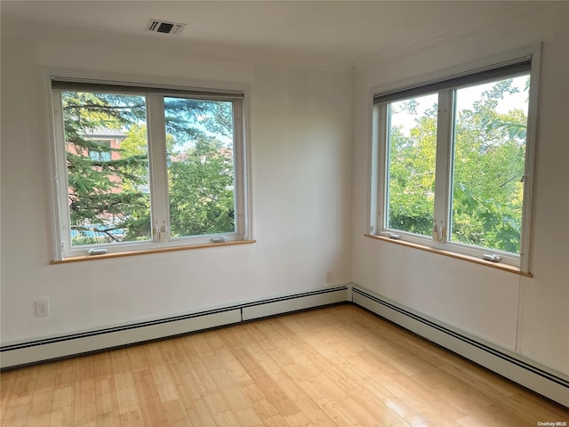 spare room with baseboard heating and light hardwood / wood-style floors