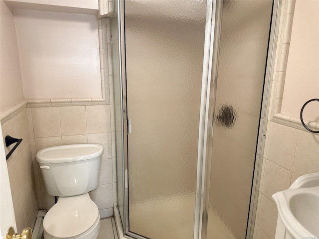 bathroom with toilet, a shower with door, tile walls, and baseboard heating