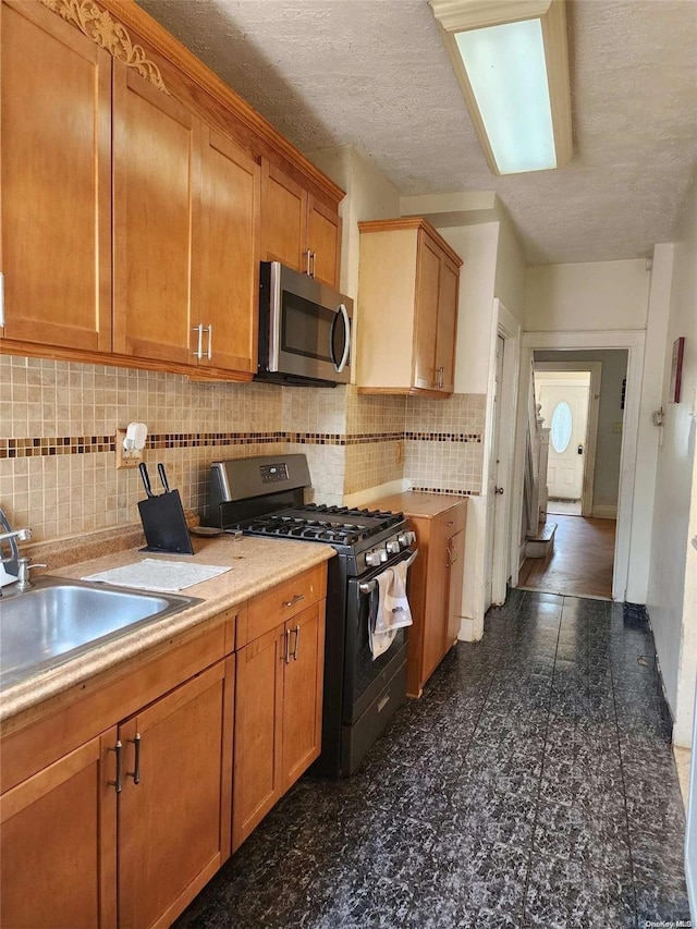 kitchen with tasteful backsplash, sink, stainless steel appliances, and a textured ceiling