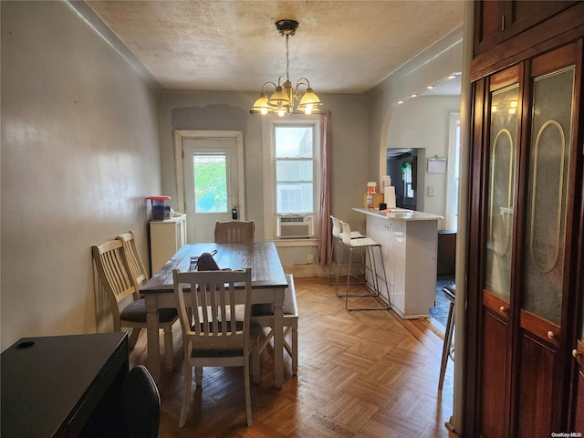 dining space with a notable chandelier, cooling unit, a textured ceiling, and light parquet floors