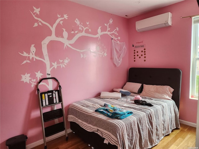 bedroom with hardwood / wood-style flooring and a wall unit AC