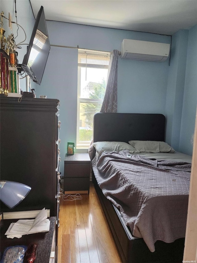 bedroom featuring a wall unit AC and hardwood / wood-style floors