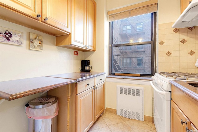 kitchen featuring decorative backsplash, light brown cabinetry, white range, light tile patterned floors, and radiator heating unit