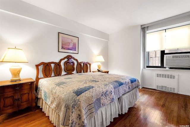 bedroom with hardwood / wood-style flooring, cooling unit, and radiator