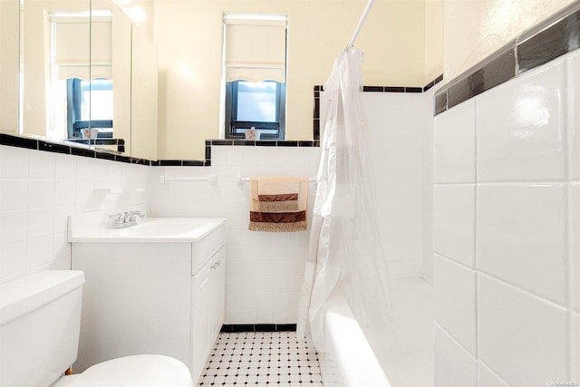 full bathroom with a healthy amount of sunlight, toilet, shower / bath combo with shower curtain, and tile walls