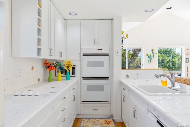 kitchen featuring tile counters, sink, backsplash, white appliances, and white cabinets