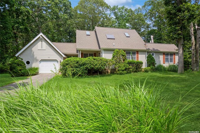 view of front facade featuring asphalt driveway, an attached garage, roof with shingles, and a front yard