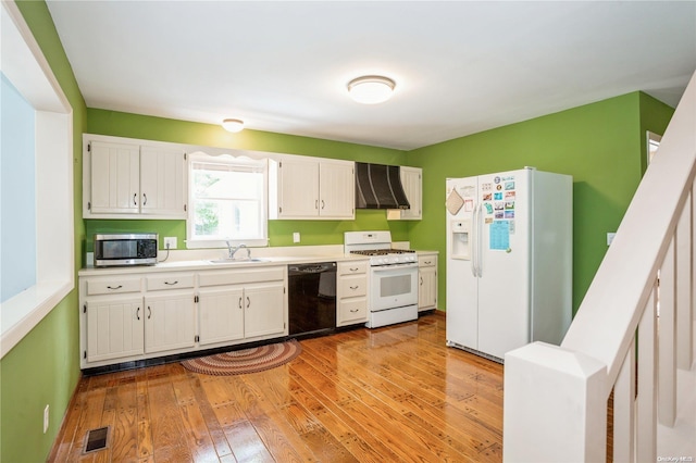 kitchen featuring wall chimney range hood, light hardwood / wood-style flooring, white cabinets, and white appliances