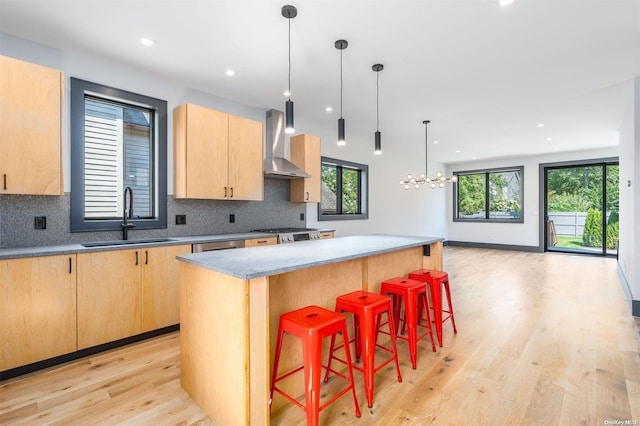 216 N St, Greenport, NY 11944 - kitchen featuring wall chimney exhaust hood, light brown cabinetry, light wood-style floors, decorative backsplash, and recessed lighting