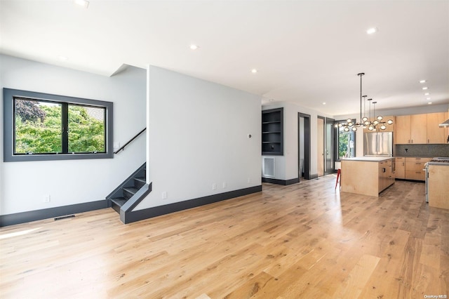 216 N St, Greenport, NY 11944 - unfurnished living room featuring stairway, healthy amount of natural light, a chandelier, recessed lighting, and light wood-style flooring