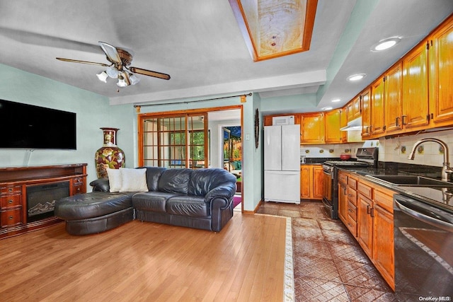 kitchen featuring ceiling fan, sink, light hardwood / wood-style flooring, backsplash, and appliances with stainless steel finishes