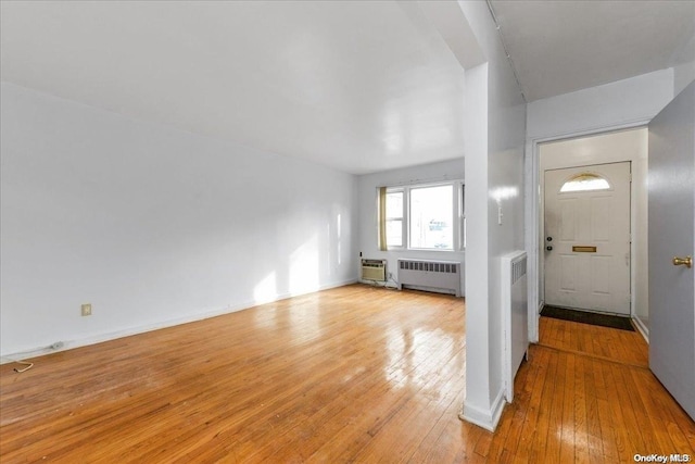 entrance foyer with a wall unit AC, radiator, and light hardwood / wood-style flooring