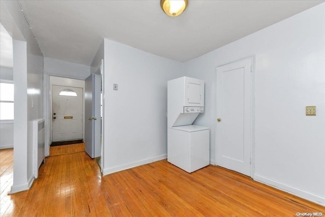 interior space featuring radiator heating unit, light wood-type flooring, and stacked washer / dryer