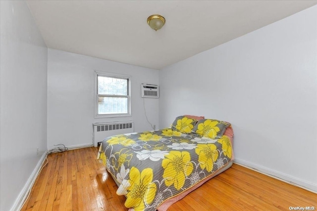 bedroom featuring wood-type flooring, a wall unit AC, and radiator