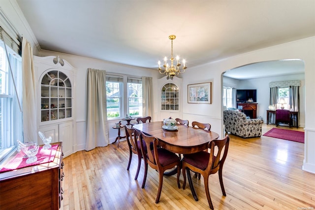 dining space with light hardwood / wood-style floors, ornamental molding, and an inviting chandelier