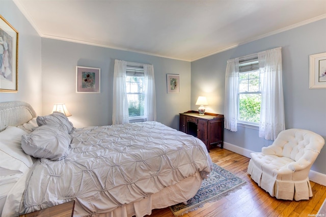 bedroom with light hardwood / wood-style floors, multiple windows, and ornamental molding