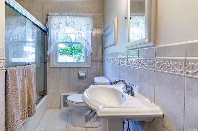 full bathroom featuring bath / shower combo with glass door, a wealth of natural light, and tile walls