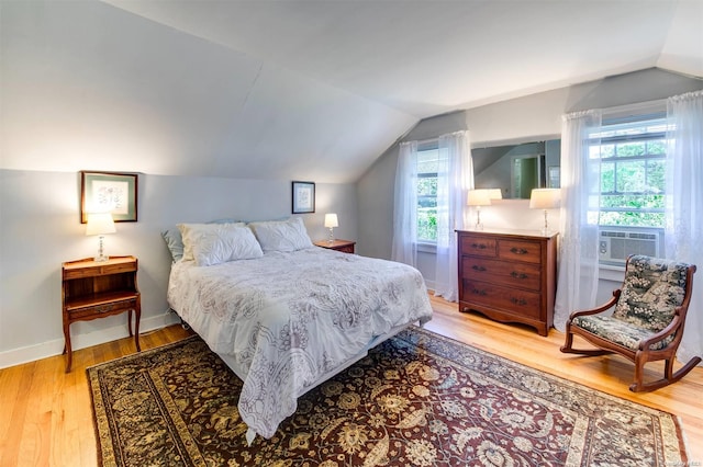 bedroom featuring cooling unit, lofted ceiling, light hardwood / wood-style flooring, and multiple windows