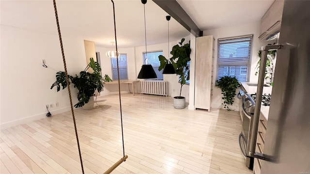 foyer entrance featuring beam ceiling, radiator heating unit, and light hardwood / wood-style floors