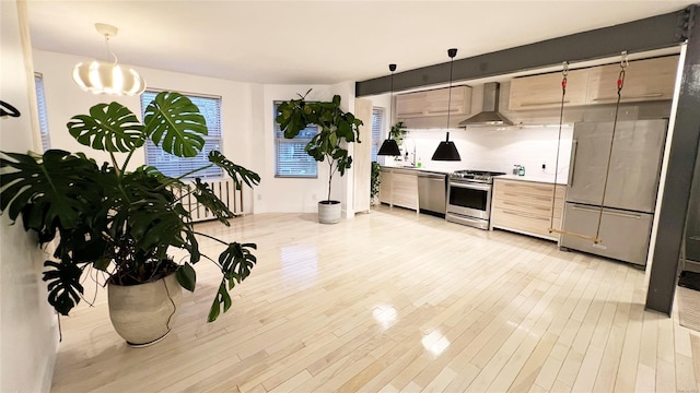 kitchen with decorative backsplash, pendant lighting, stainless steel appliances, and wall chimney range hood