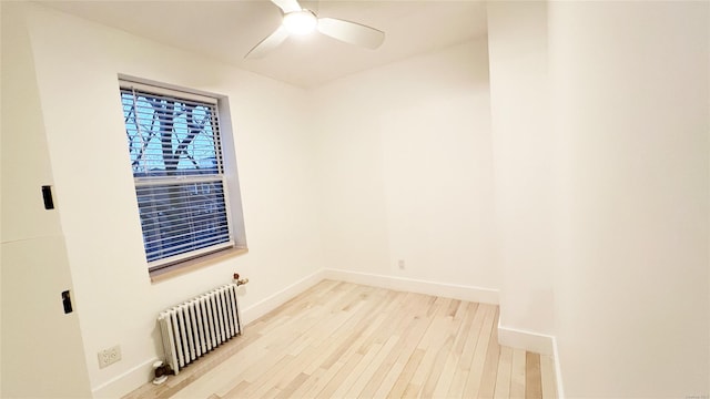 spare room featuring ceiling fan, light hardwood / wood-style floors, and radiator