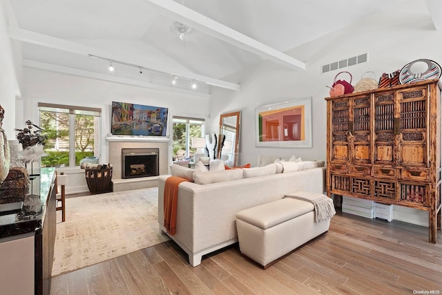 living room featuring plenty of natural light, vaulted ceiling, light wood-type flooring, and a tiled fireplace