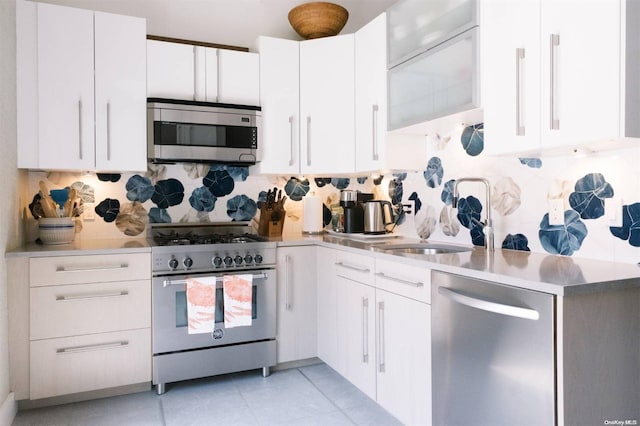 kitchen featuring white cabinetry, sink, stainless steel appliances, decorative backsplash, and light tile patterned flooring