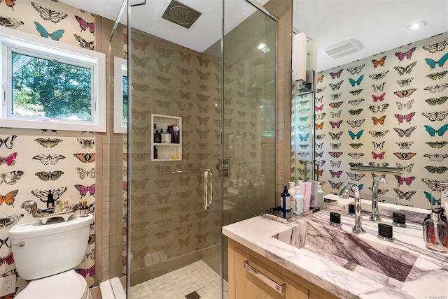 bathroom featuring vanity, toilet, and a shower with shower door