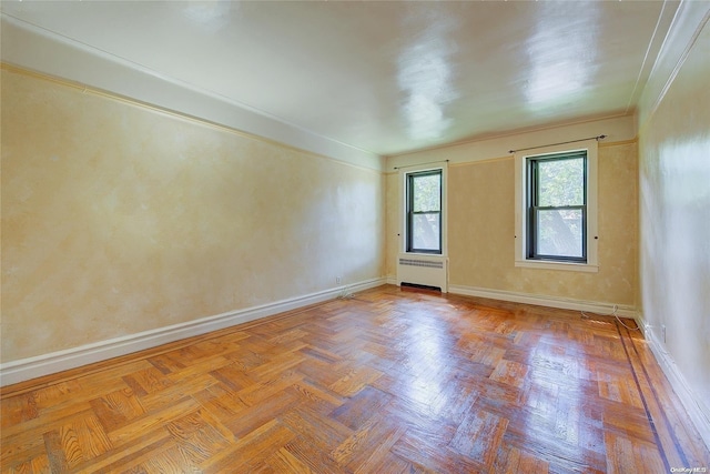 unfurnished room with radiator, light parquet floors, and ornamental molding