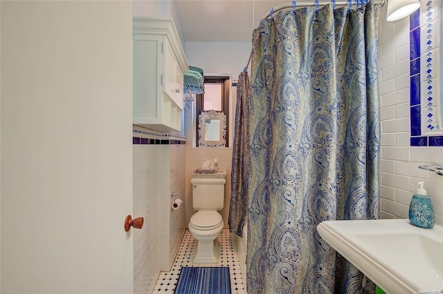 bathroom with tile patterned floors, toilet, and tile walls